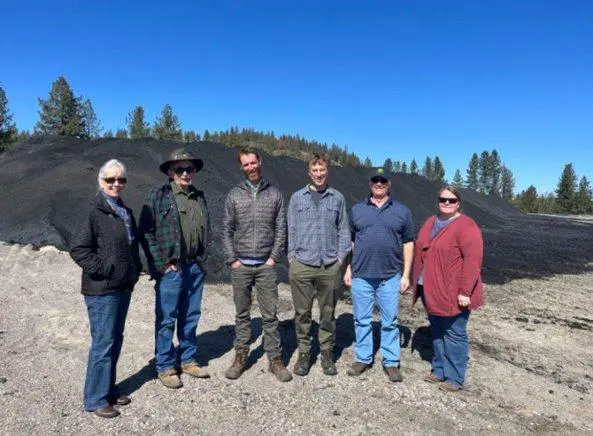 Staff from Myno Carbon, Stevens County Conservation District, and WSU Extension in front of biochar product in Kettle Falls, Washington